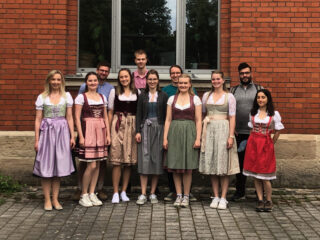 BVT representation wearing traditional clothing in front of red brick building